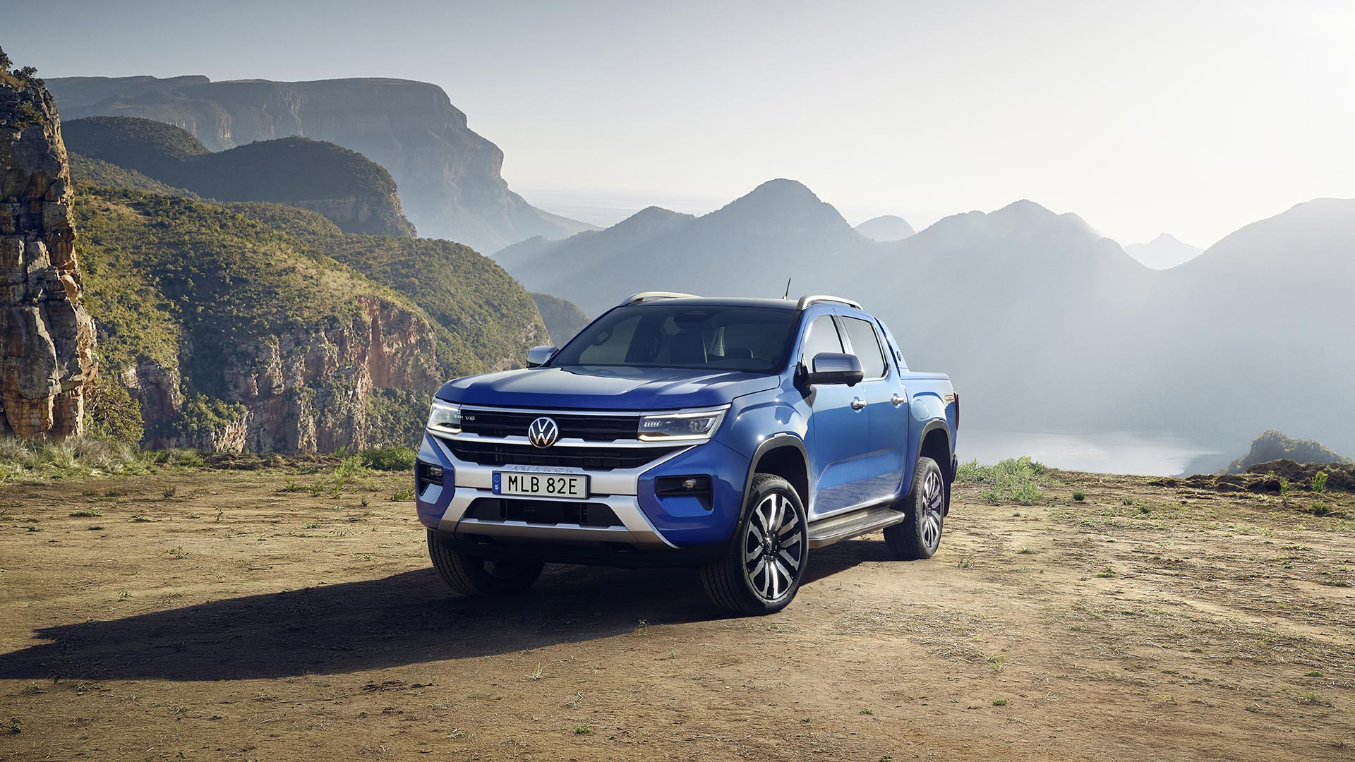 Blå Amarok Aventura snett framifrån, med dimmiga berg i bakgrunden