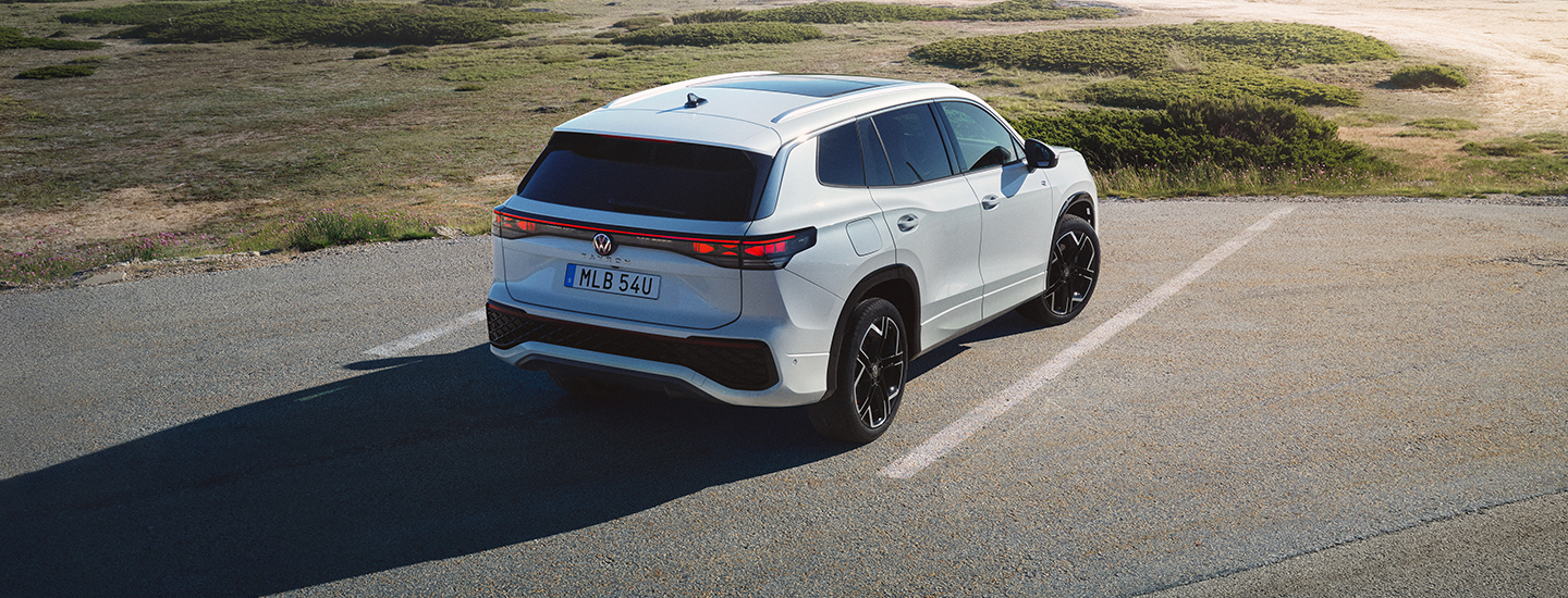 Vit Volkswagen Tayron står parkerad intill en strand.