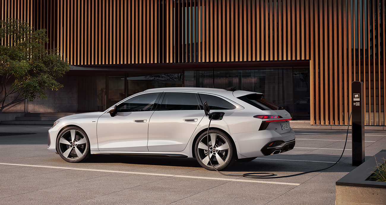 Audi A6 Avant e-hybrid quattro i silvergrå metallic står parkerad med laddsladden i